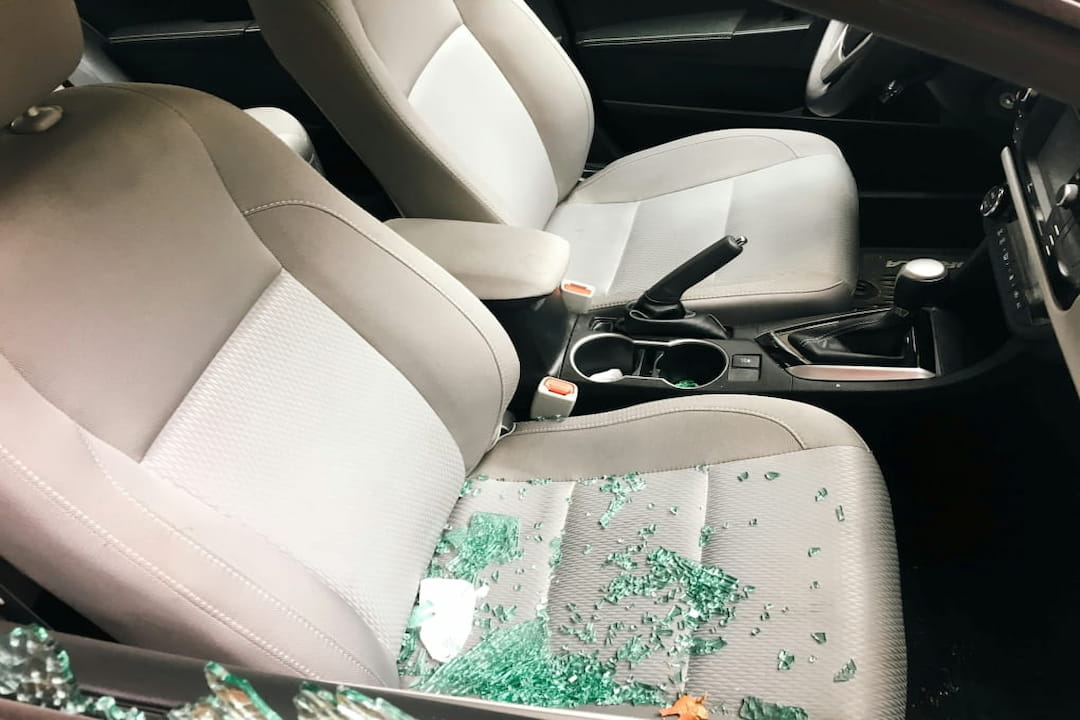 car interior with shattered window glass on the seat, showing signs of a break-in