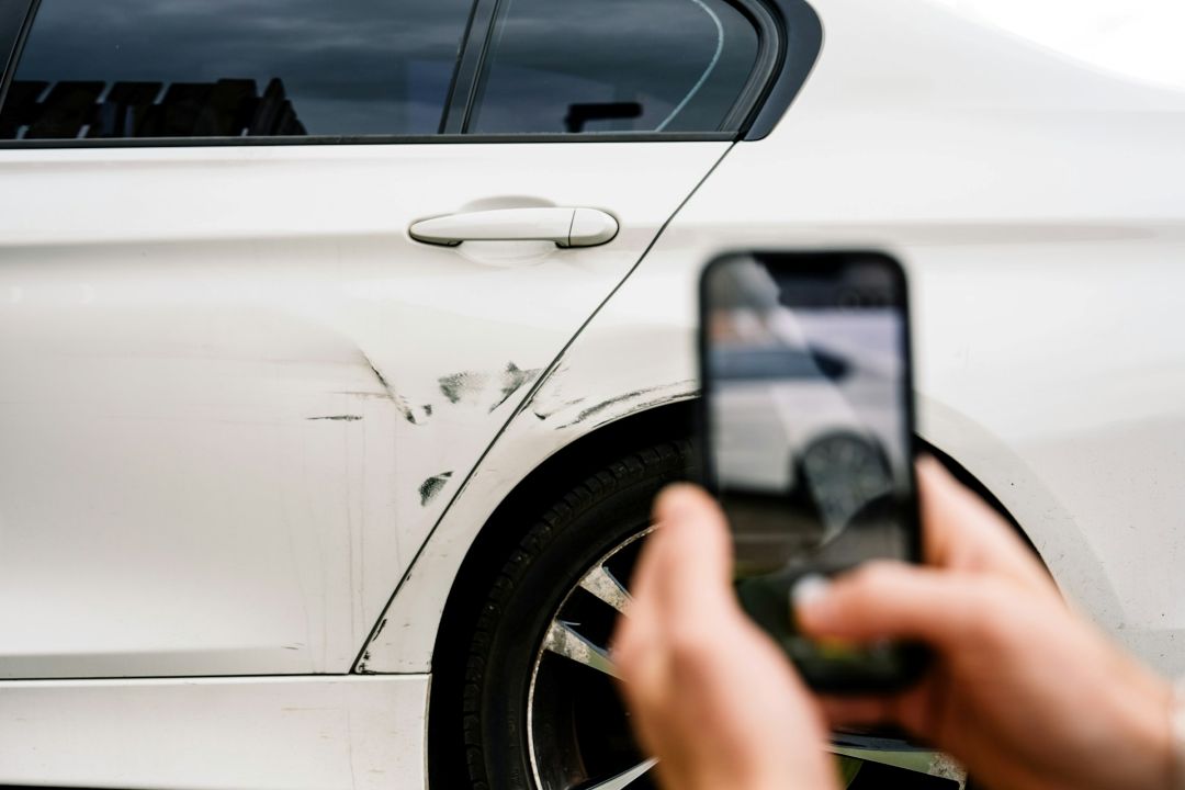 person photographing cosmetic scratches and scuff marks on the rear door