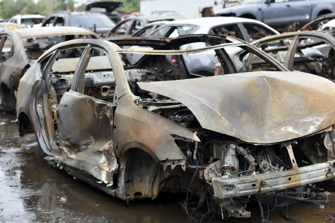 burned and heavily damaged cars in a salvage yard, showing catastrophic fire damage