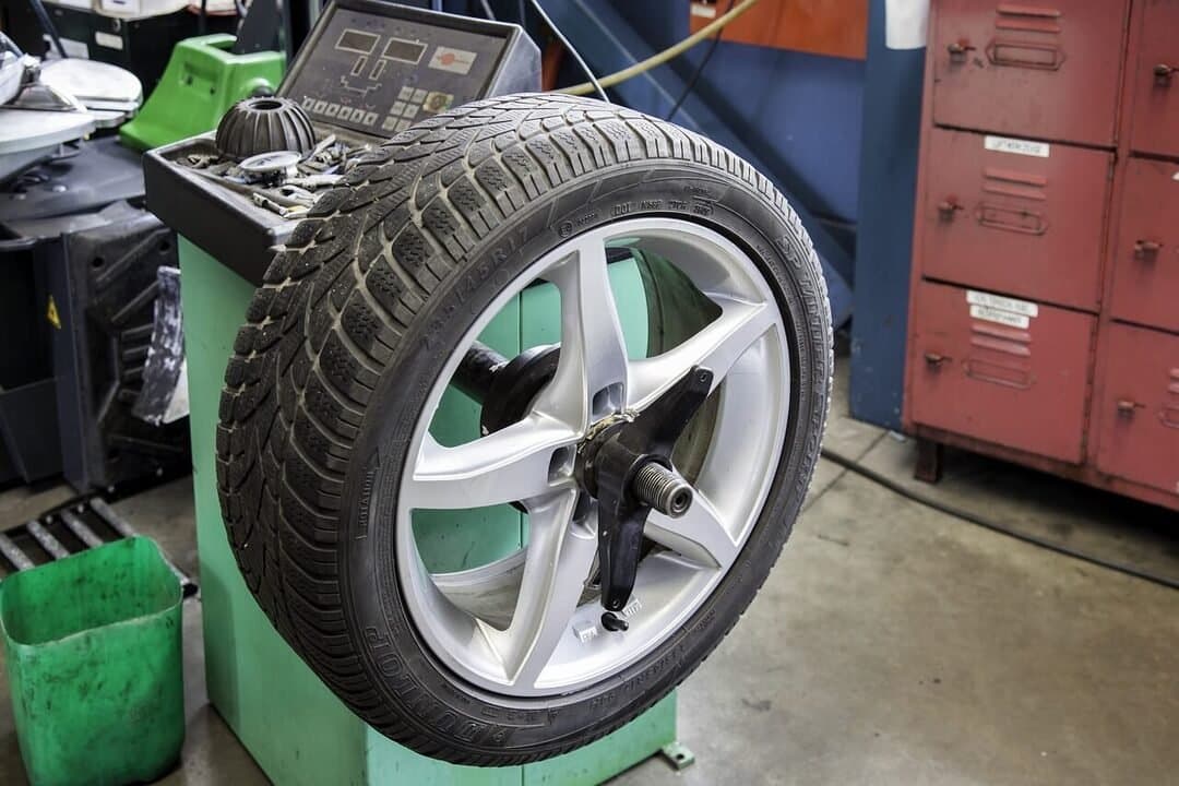 close-up of a car tire with a silver alloy wheel mounted on a wheel balancing machine