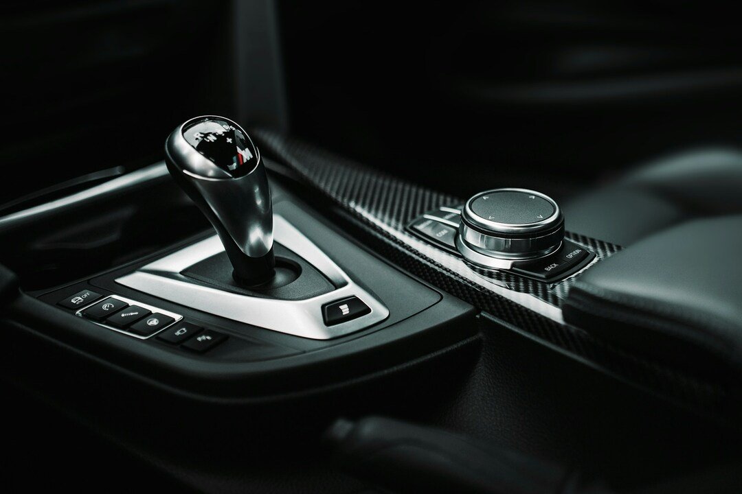 close-up of a modern car's automatic gear shifter and rotary infotainment control knob