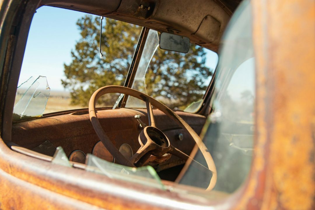 rusty abandoned car interior viewed through a broken window