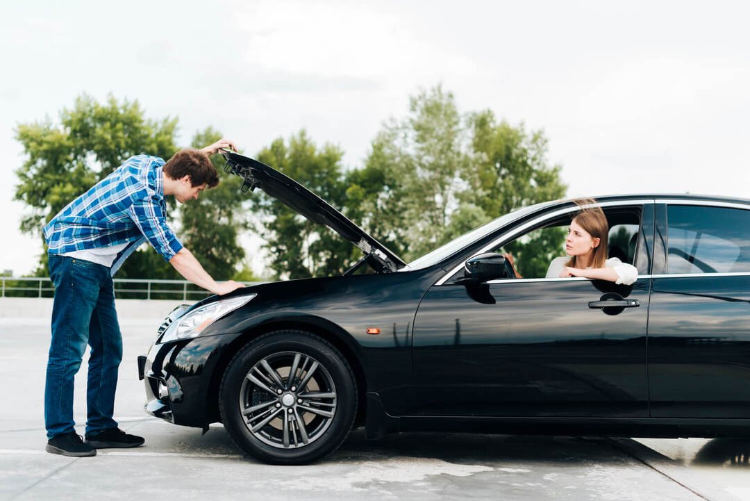 a man checking a car on the road