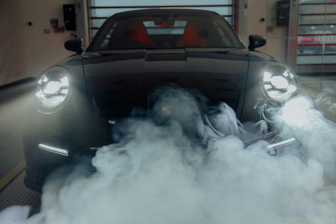 sports car surrounded by thick exhaust smoke inside a garage