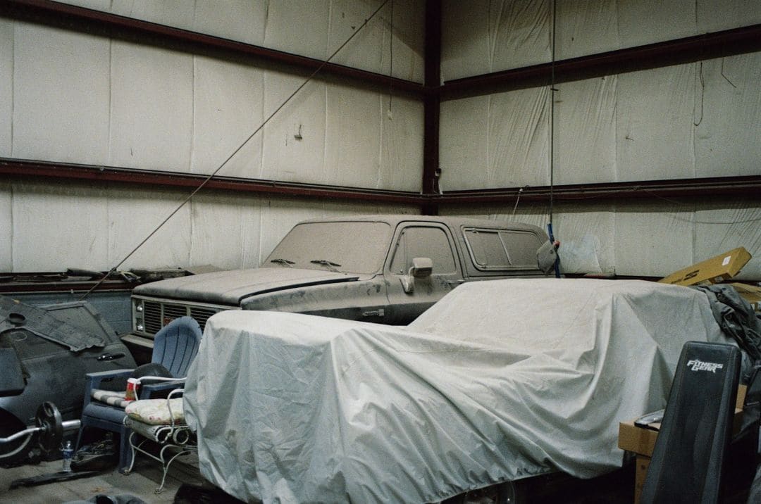 dust-covered classic cars stored indoors under breathable car covers